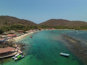 A coastal area with clear turquoise waters, a sandy beach, and a small boat docked near the shore.