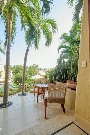A patio area with a table and chairs, surrounded by palm trees and potted plants.
