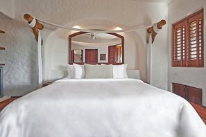 Un dormitorio con una cama grande, cabecera de madera y ventilador de techo.