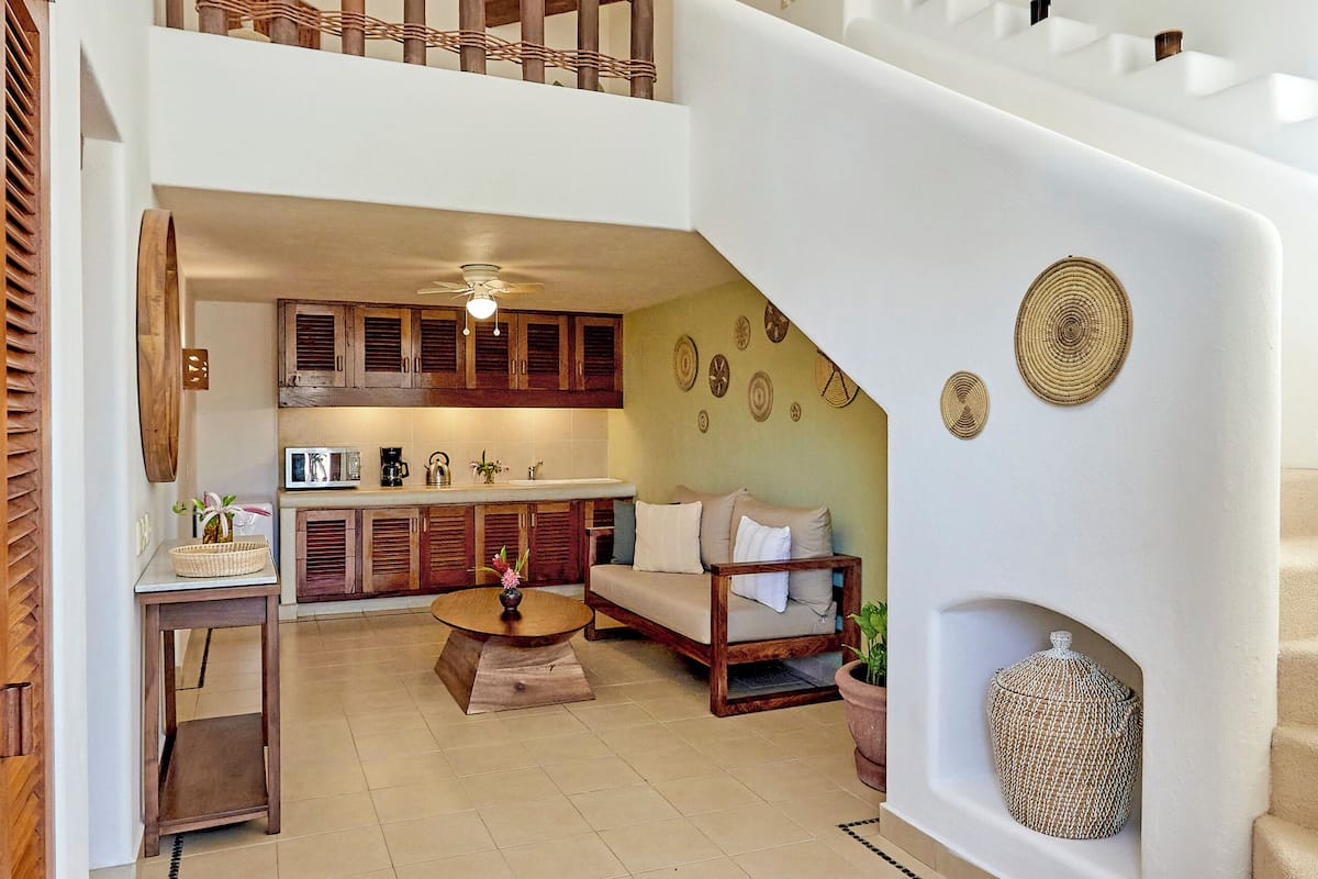 Un vaste espace de vie doté d’un haut plafond, d’un escalier, d’une cuisine et d’un coin salon.