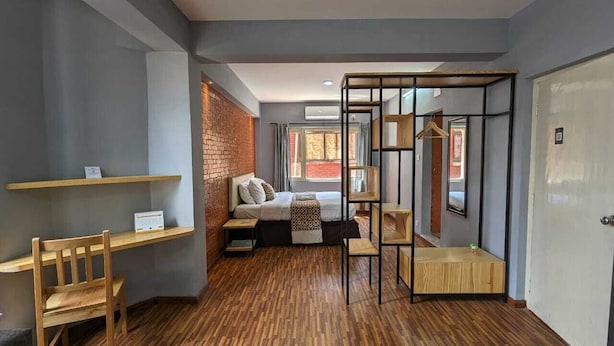 A modern bedroom with a bed, a wooden desk, and a hanging chair. - Nyadha House (Lalitpur)