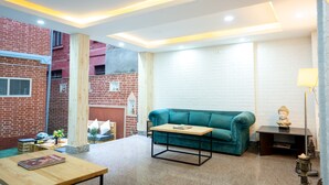 A modern living room with a green sofa, wooden coffee table, and a brick wall. - Nyadha House (Lalitpur)