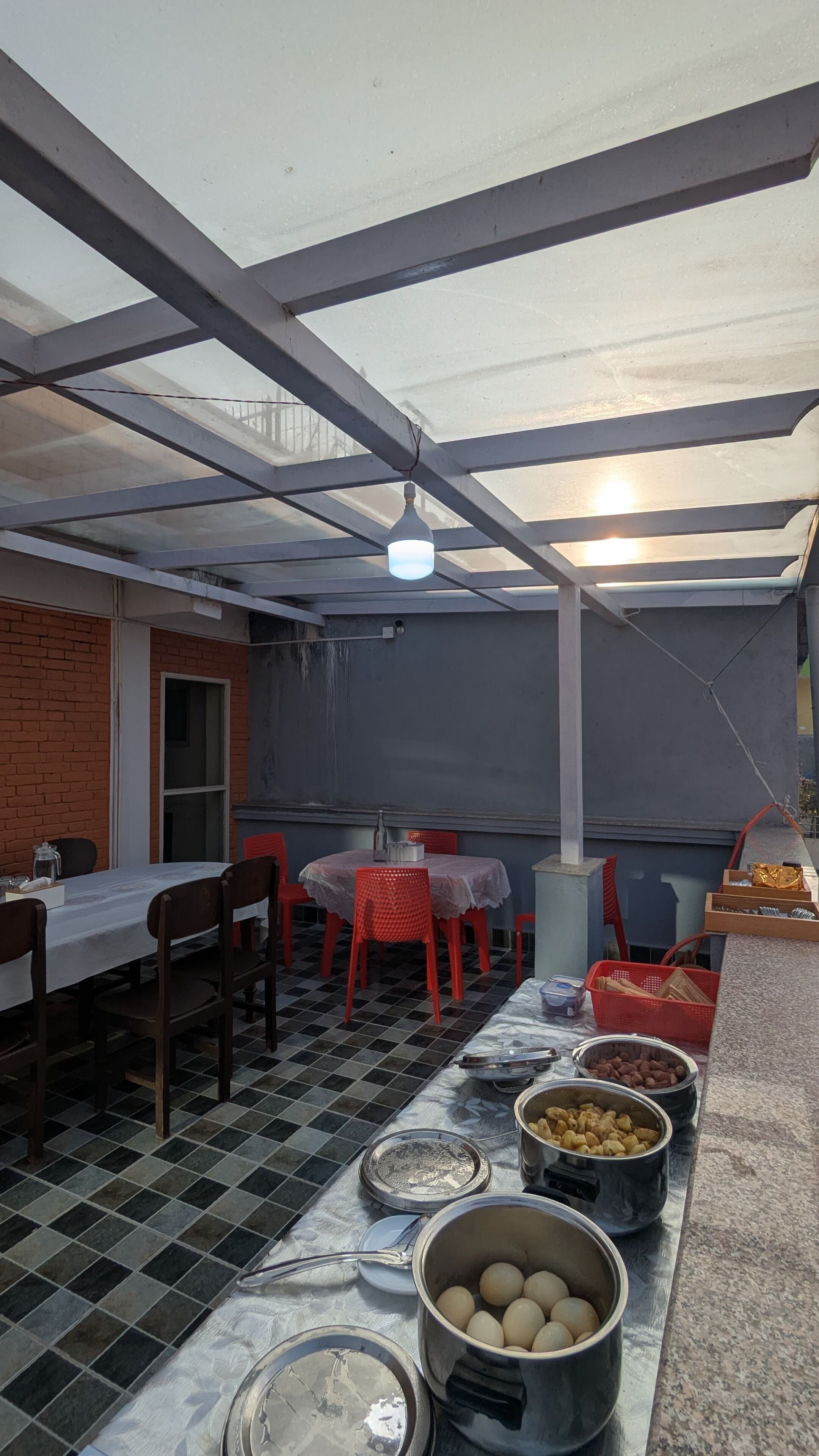 A covered outdoor dining area with a table, chairs, and food containers.