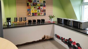 Une cuisine moderne dotée d’un espace dédié au café, d’une décoration murale représentant des fruits et d’un four à micro-ondes.