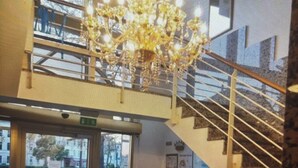 Un intérieur moderne avec un escalier, un lustre et un coin salon.