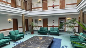 Un hall d’entrée spacieux avec une table centrale en marbre, des canapés verts et des plantes en pot.