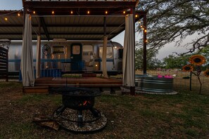 A covered outdoor area with a fire pit, a portable toilet, and a water feature.