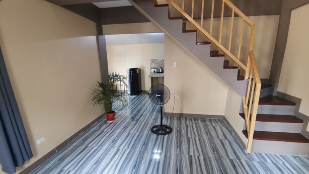 Un couloir doté d’un sol en marbre, d’un escalier en bois et d’un ventilateur.