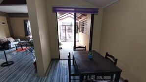 Un coin repas avec une table et des chaises, une plante en pot et une vue sur un espace extérieur abrité.