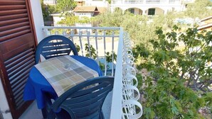 En balkong med ett bord och stolar, med utsikt över ett bostadsområde med hus och grönområden.