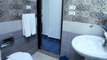 A bathroom with patterned tiles, a white sink, and a towel rack.