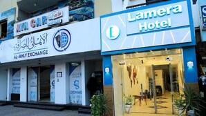 A hotel entrance with a glass door, a sign for 'Lamera Hotel', and a car rental service 'Aya Car' and 'Al-Ahly Exchange' nearby. - Lamera Hotel. (Hurghada)