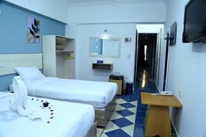 A hotel room with two beds, a small table, a mirror, a wardrobe, and a hallway leading to the exit. - Lamera Hotel. (Hurghada)