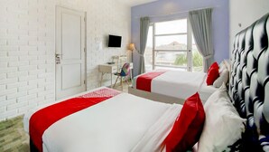 A hotel room with two beds, a desk, a TV, and a window with curtains. - OYO 3939 Omahkoe Guest House Syariah (Malang)