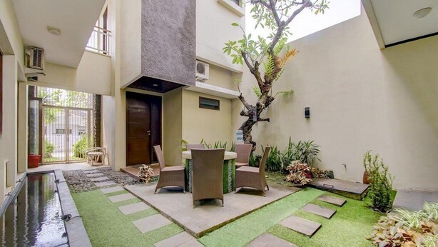 A modern building with a courtyard featuring a small pool, outdoor seating, and a tree. - OYO 3939 Omahkoe Guest House Syariah (Malang)