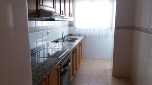 A kitchen with granite countertops, stainless steel appliances, and wooden cabinets. - Apartamentos Oropesa sin Piscina 3000 (Oropesa del Mar)
