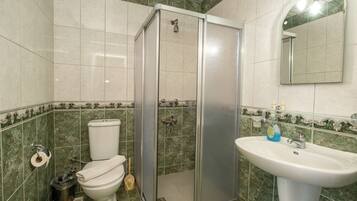 A bathroom with a toilet, a shower enclosure, and a sink.