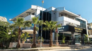 A modern hotel with a prominent Infinity sign, featuring a glass facade and palm trees in the foreground.