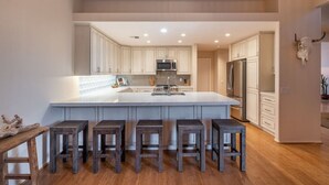 Une cuisine moderne dotée d’un grand îlot central, de meubles blancs et d’une décoration représentant une tête de taureau.