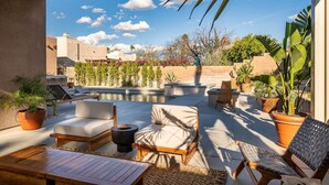 Une terrasse sur le toit avec des sièges extérieurs, une piscine et des plantes en pot.