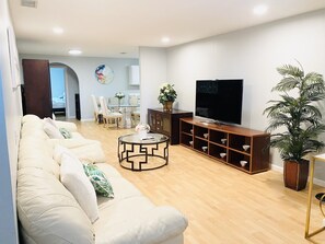 A living room with a sofa, a coffee table, a TV, and a plant.