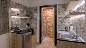 A modern kitchen with patterned tiles, wooden cabinets, a built-in oven, and a stainless steel sink. - Parko Studios - Studio 1 (Rodos)