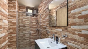 A modern bathroom with a glass shower enclosure, a white sink, and a mirror. - Parko Studios - Studio 1 (Rodos)