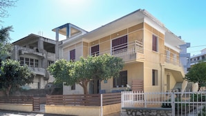 A two-story building with a balcony, a gated entrance, and a tree in front. - Parko Studios - Studio 1 (Rodos)