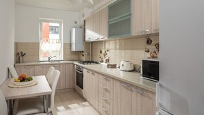 A modern kitchen with light wood cabinets, a stainless steel sink, a gas stove, and a built-in microwave. - Brasov Holiday Apartments-purple (Brasov)