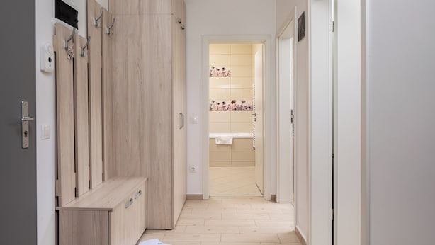 A hallway with a wooden bench, a pair of slippers, and a bathroom visible in the distance. - Brasov Holiday Apartments-purple (Brasov)