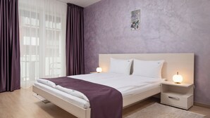 A modern bedroom with a bed, nightstands, and a wall-mounted picture. - Brasov Holiday Apartments-purple (Brasov)
