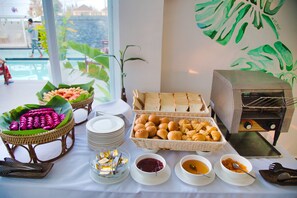 A buffet table with various food items, including pastries and bread, and a toaster oven. - Naiya Sea Resort (Sihanoukville)