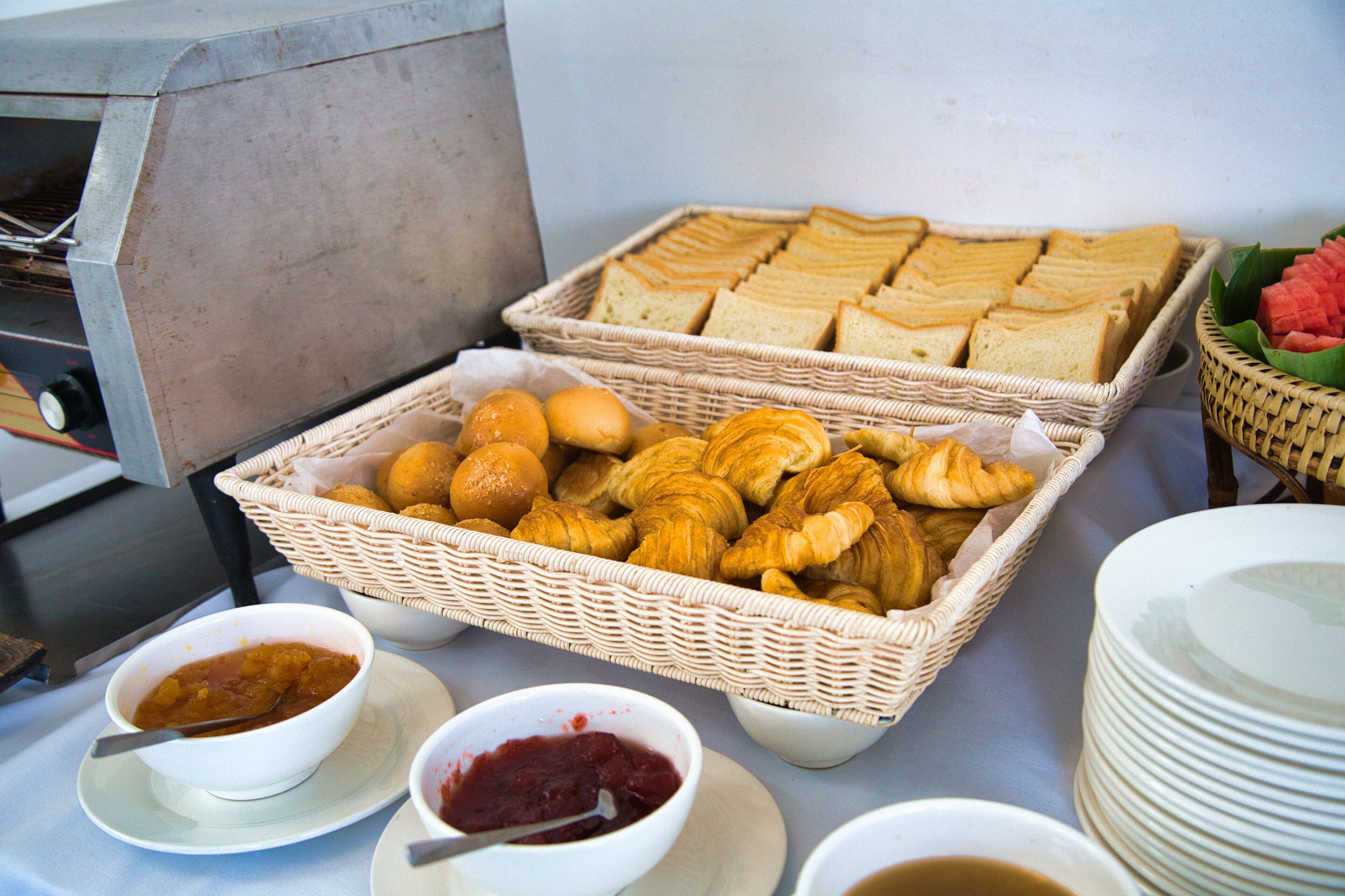 Ein Frühstücksbuffet mit Brot, Croissants und Marmeladen.