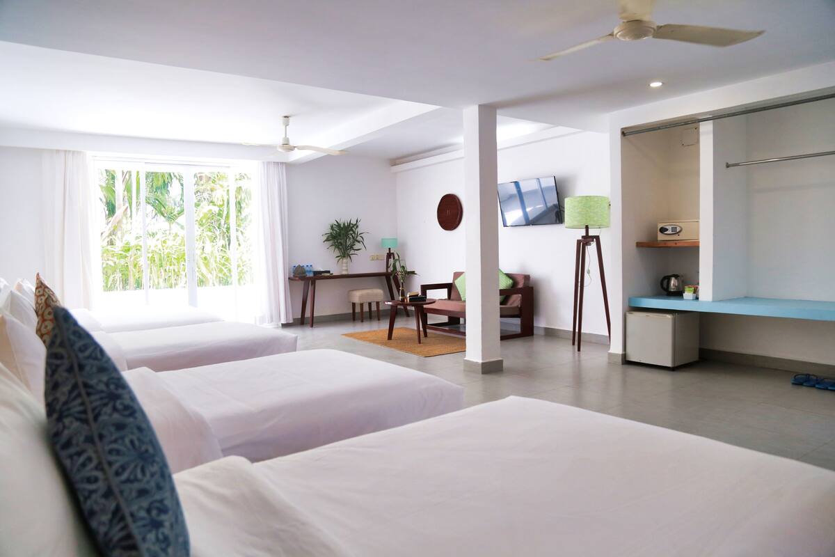 A hotel room with two beds, a desk with a chair, a TV, and a wardrobe.