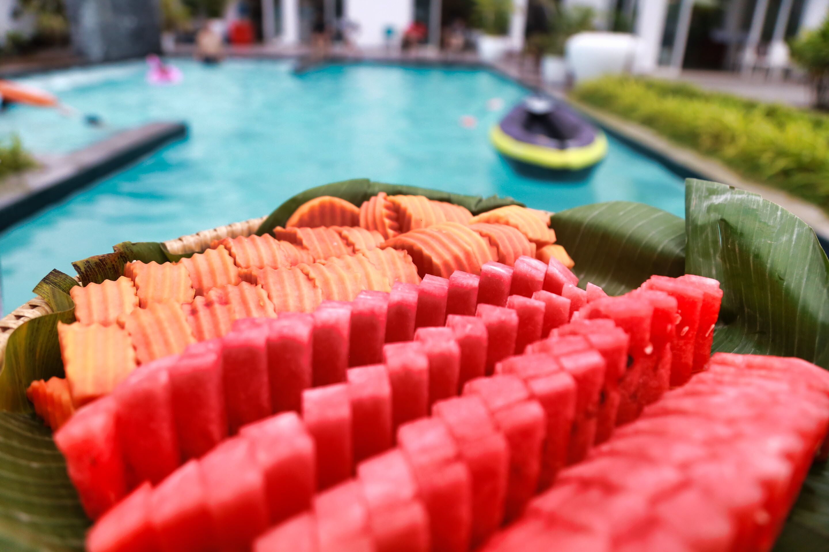 Una piscina con un vassoio di foglie di banano e anguria e melone a fette.