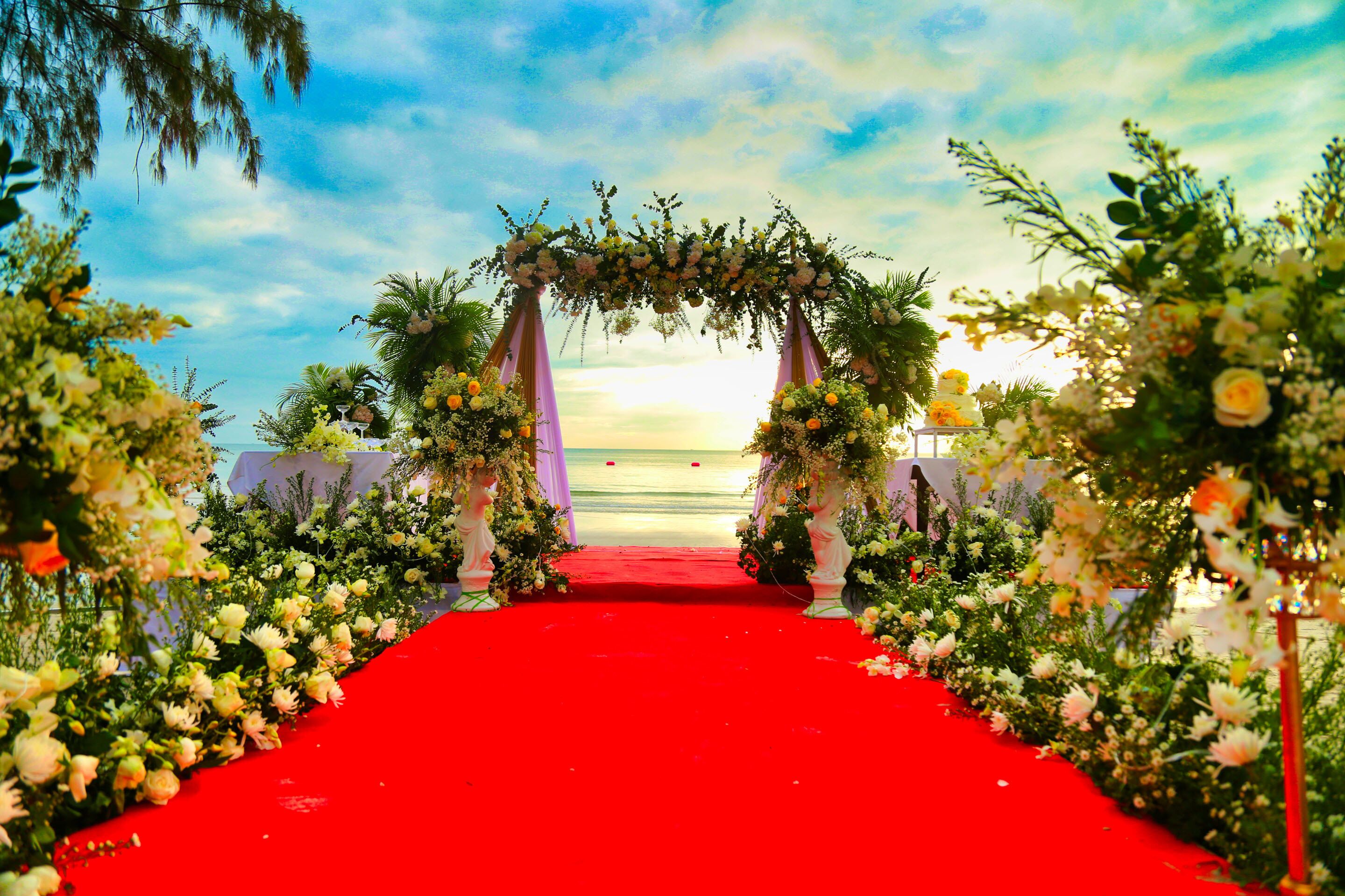 Una alfombra roja que conduce a un arco floral con vista al océano.