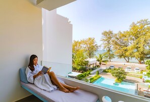 A person sitting on a balcony with a view of a swimming pool and greenery. - Naiya Sea Resort (Sihanoukville)