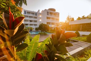 A modern hotel with a pool, surrounded by lush greenery and a clear sky. - Naiya Sea Resort (Sihanoukville)