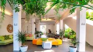 Ein modernes Wohnzimmer mit einem gelben Sofa, grünen Kissen und Topfpflanzen.