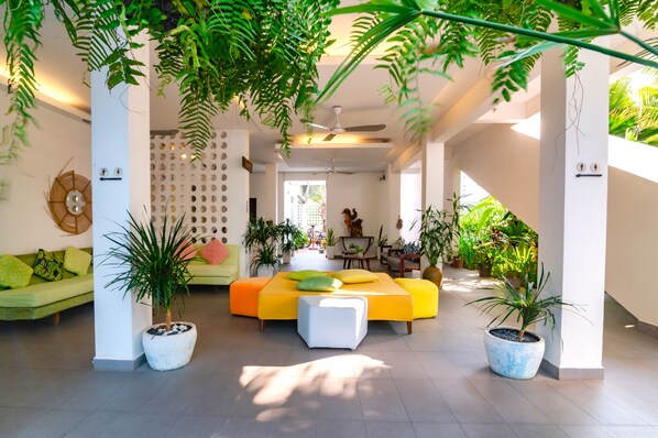 A modern living room with a yellow sofa, green cushions, and potted plants. - Naiya Sea Resort (Sihanoukville)
