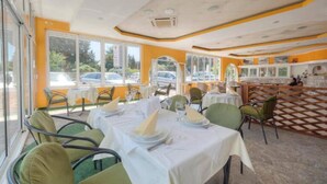 A restaurant with outdoor seating, tables set with white tablecloths and green chairs, and a checkered floor pattern.