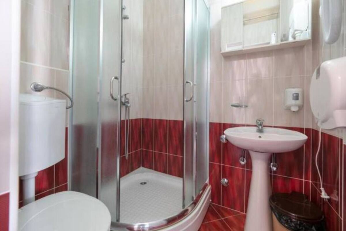A bathroom with a glass-enclosed shower, a white sink, and a toilet.