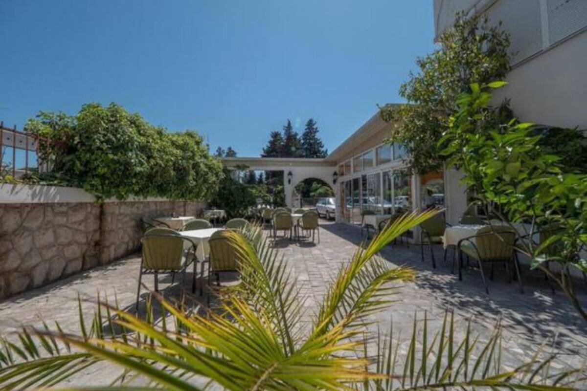 An outdoor patio area with tables and chairs, surrounded by stone walls and greenery.