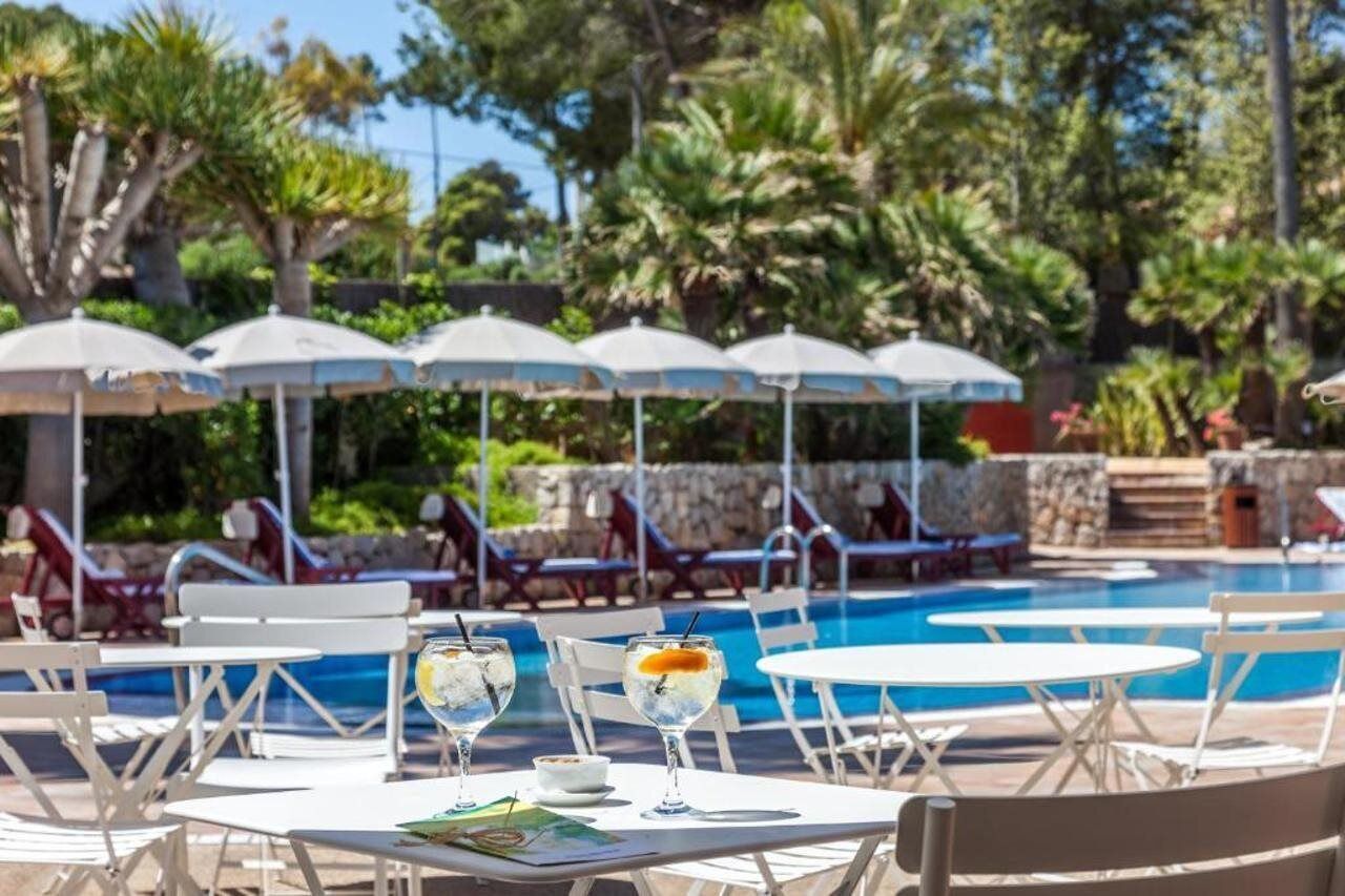 A poolside area with lounge chairs and umbrellas, a pool, and a dining table with a menu.