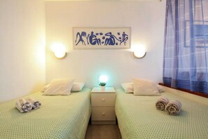 Une chambre d’hôtel avec deux lits, une table de chevet, une œuvre d’art accrochée au mur et une fenêtre avec un rideau.