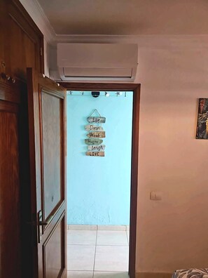 An interior hallway with a wooden door, an air conditioning unit, and a wall-mounted sign with motivational phrases.