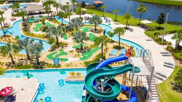 Parque acuático con una piscina grande, toboganes y una zona de campo de golf.