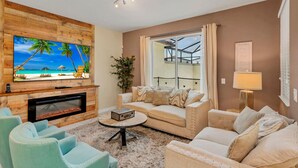 Una sala de estar con chimenea, un televisor de pantalla plana grande, un sofá y una mesa de centro.