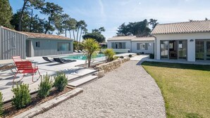 Une villa moderne dotée d’une piscine, d’un espace salon extérieur et d’une pelouse bien entretenue.