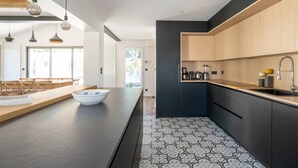 Une cuisine moderne avec des meubles de couleur sombre, un plan de travail en bois et un revêtement mural décoratif.